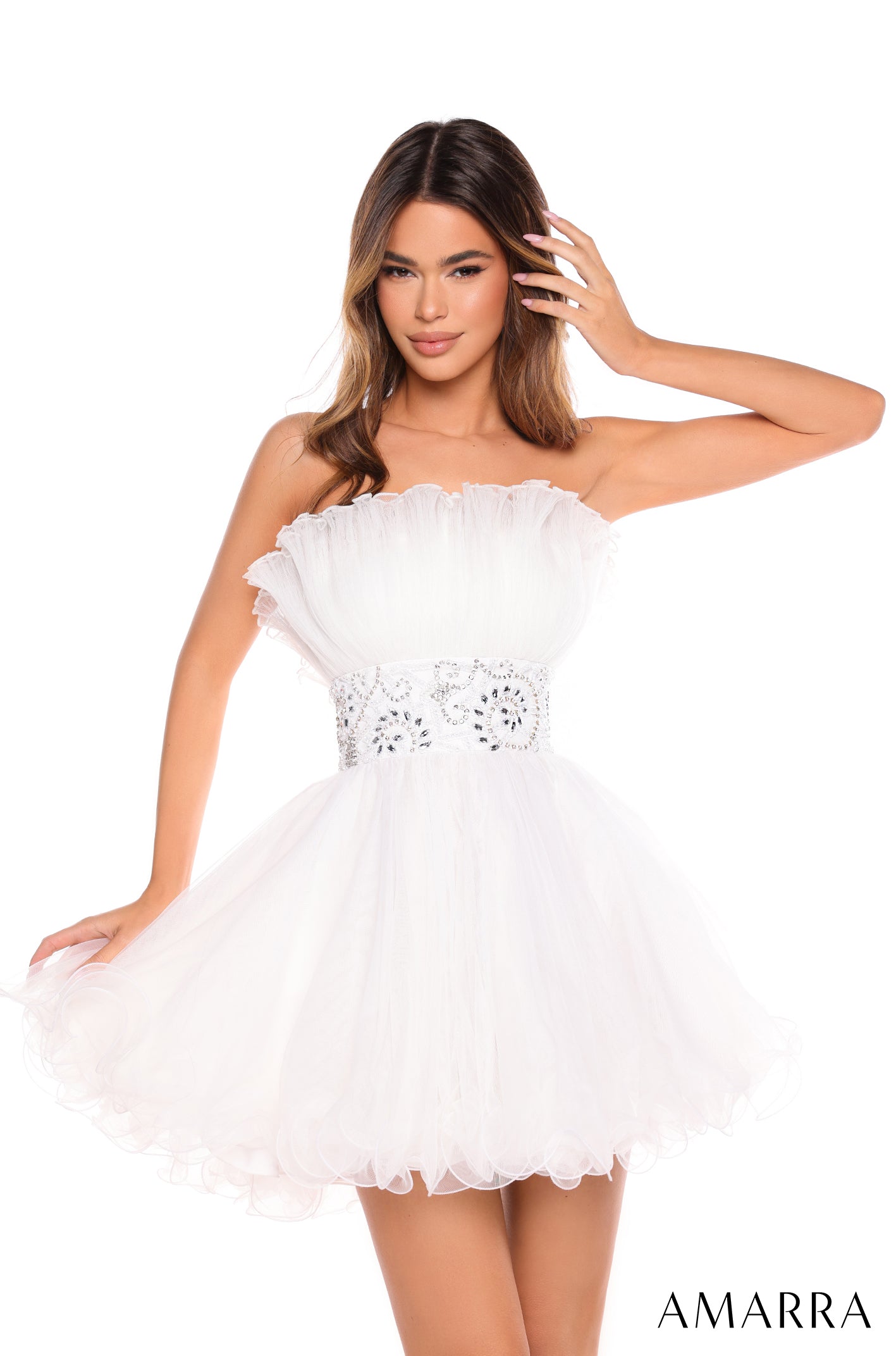 A slim model wears a strapless, ruffled Ivory tulle dress with a jeweled waistband.