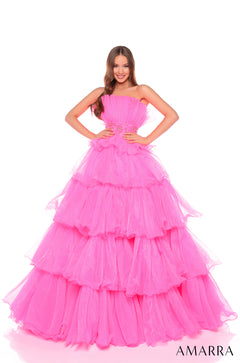 A woman wears a strapless, tiered Hot Pink ball gown with a beaded waistline by Amarra.