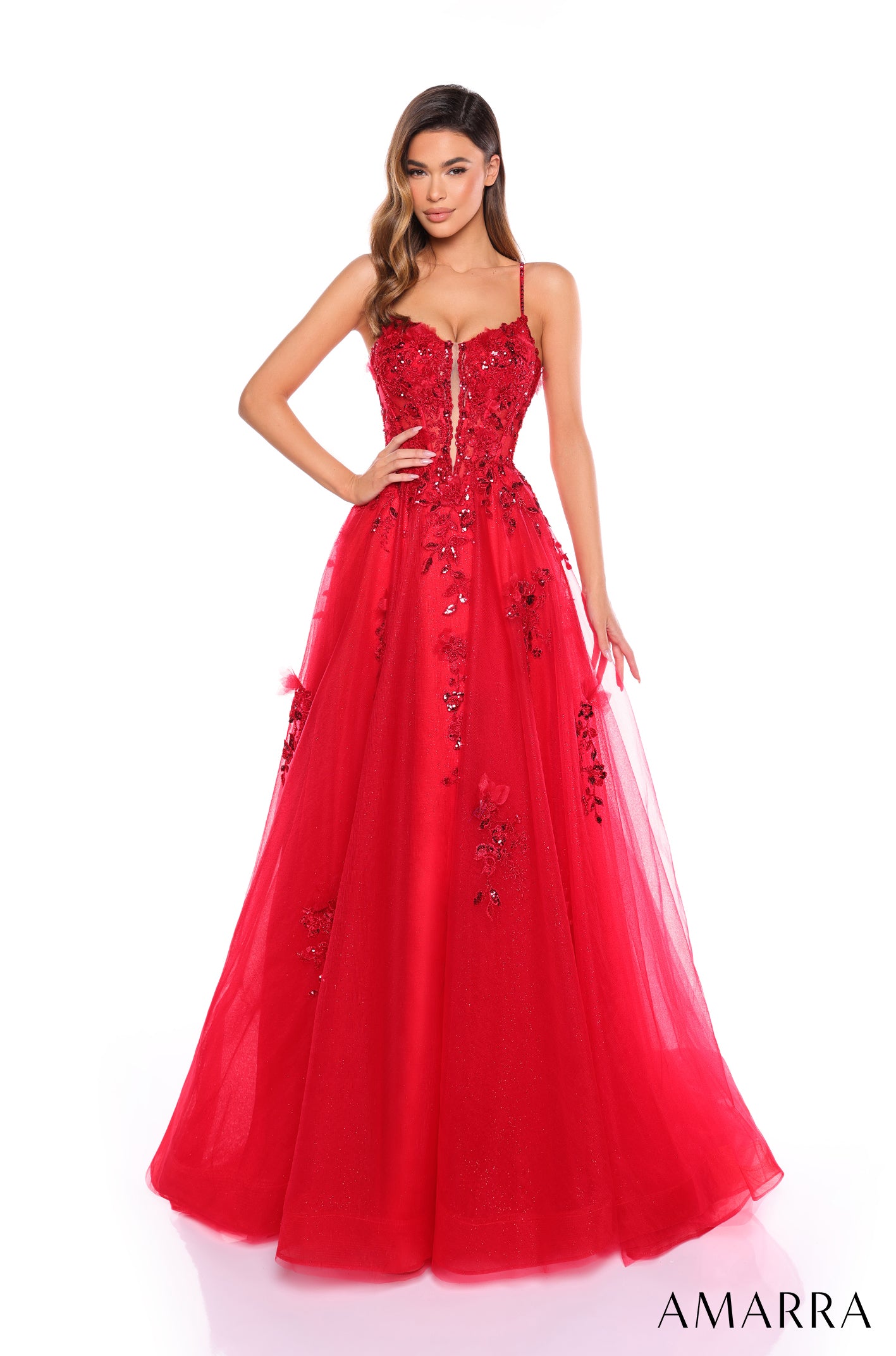 A woman wears a red spaghetti strap ball gown with sequined floral appliqués and a full tulle skirt.