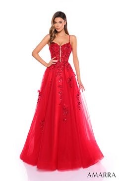 A woman wears a red spaghetti strap ball gown with sequined floral appliqués and a full tulle skirt.