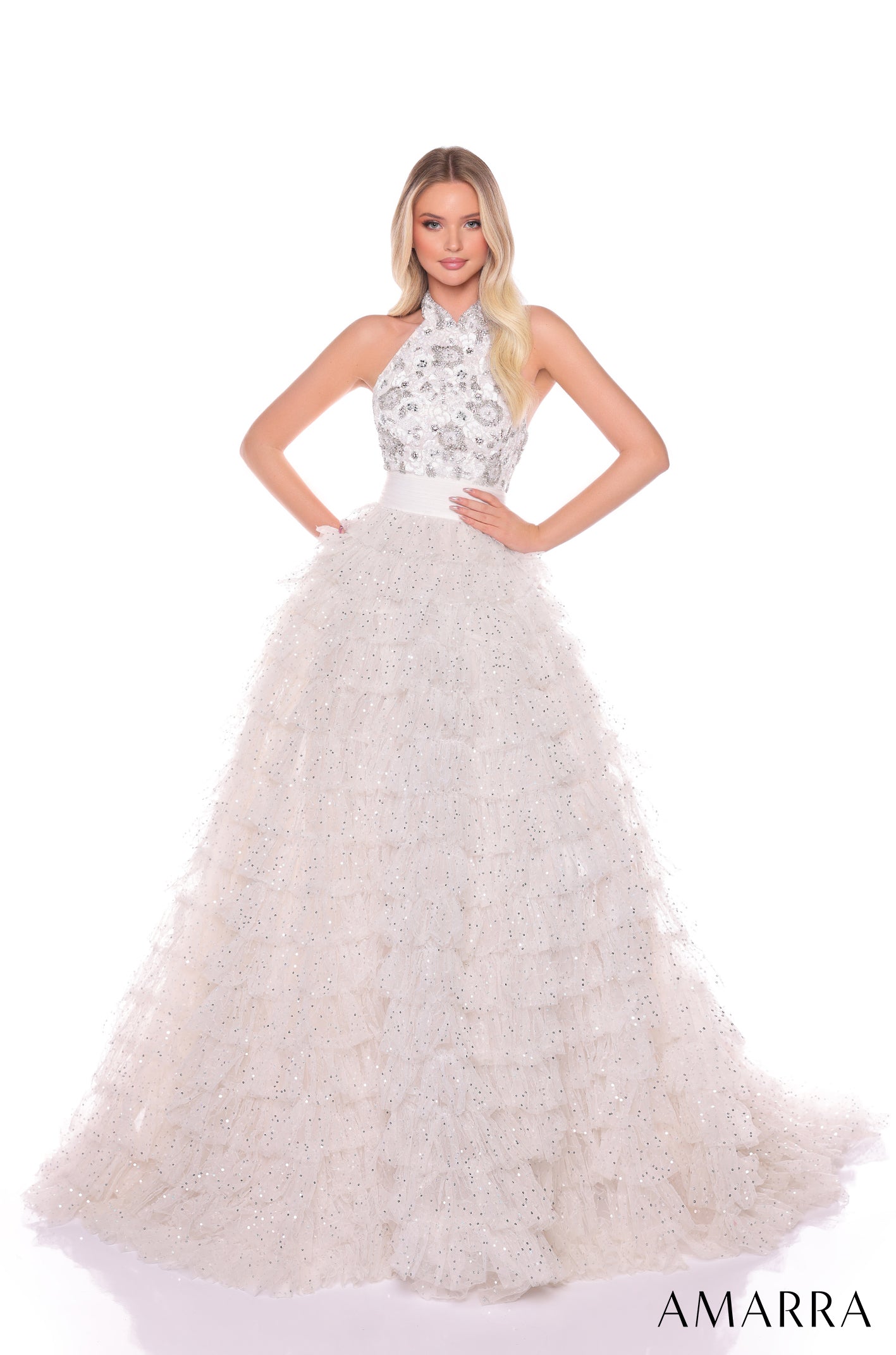 A model wears a sparkling Ivory/Silver halter ball gown with a beaded bodice and full, layered skirt.