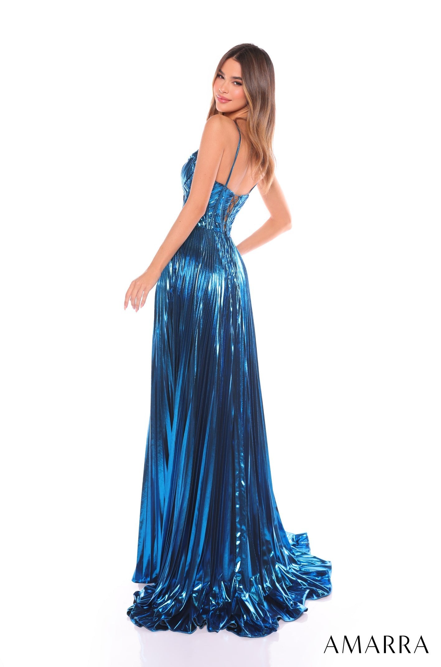 A model wears a metallic blue pleated gown with thin straps and a flowing train.