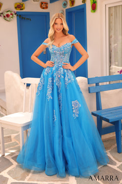 A woman wears a stunning turquoise off-shoulder ball gown with intricate floral lace appliqués.