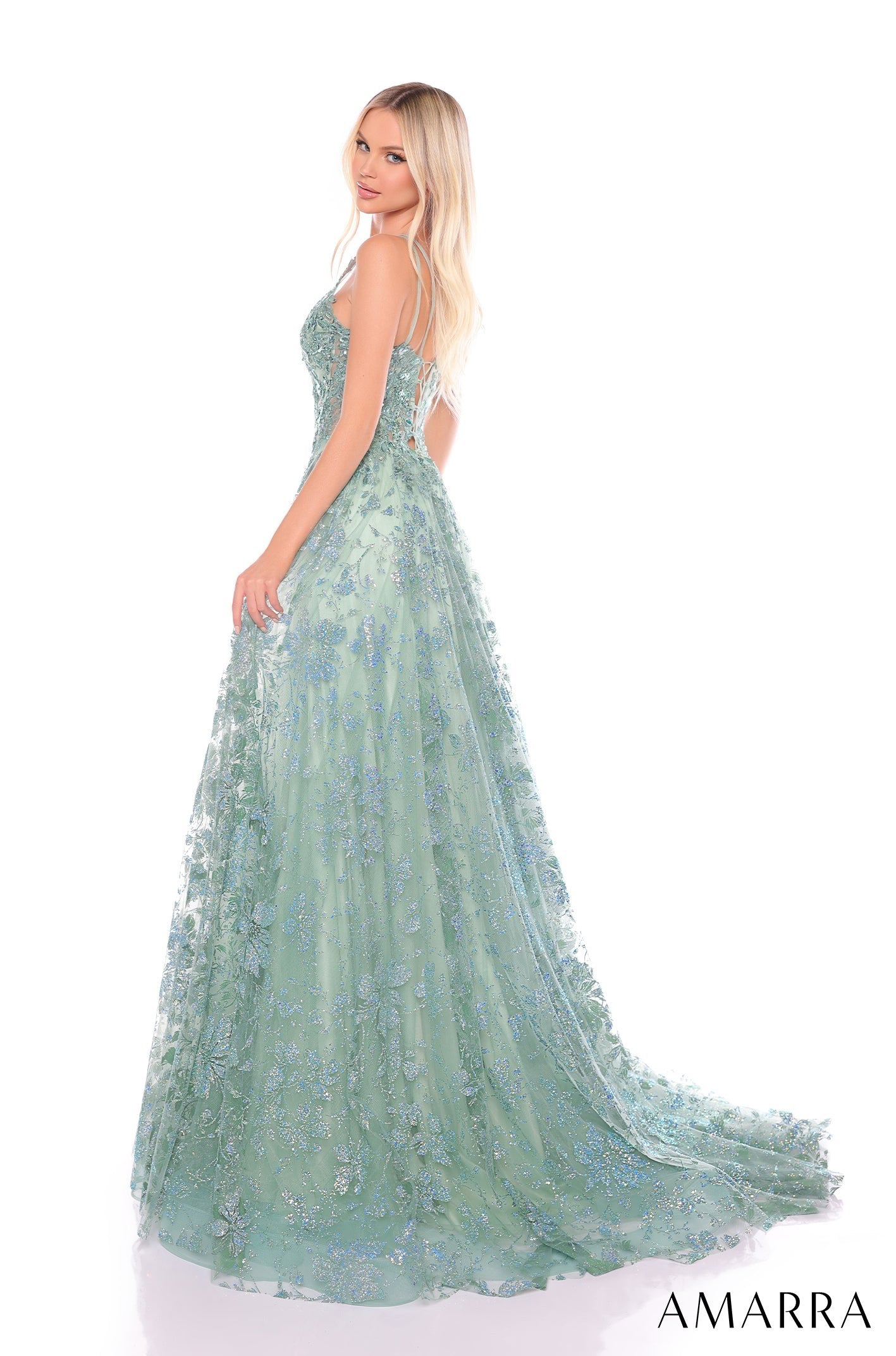 A model wears a sage green, sparkly, floor-length gown with delicate floral lace and a flowing train.