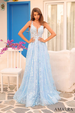 A tall, elegant model wears a flowing light blue lace evening gown against a blue door backdrop.
