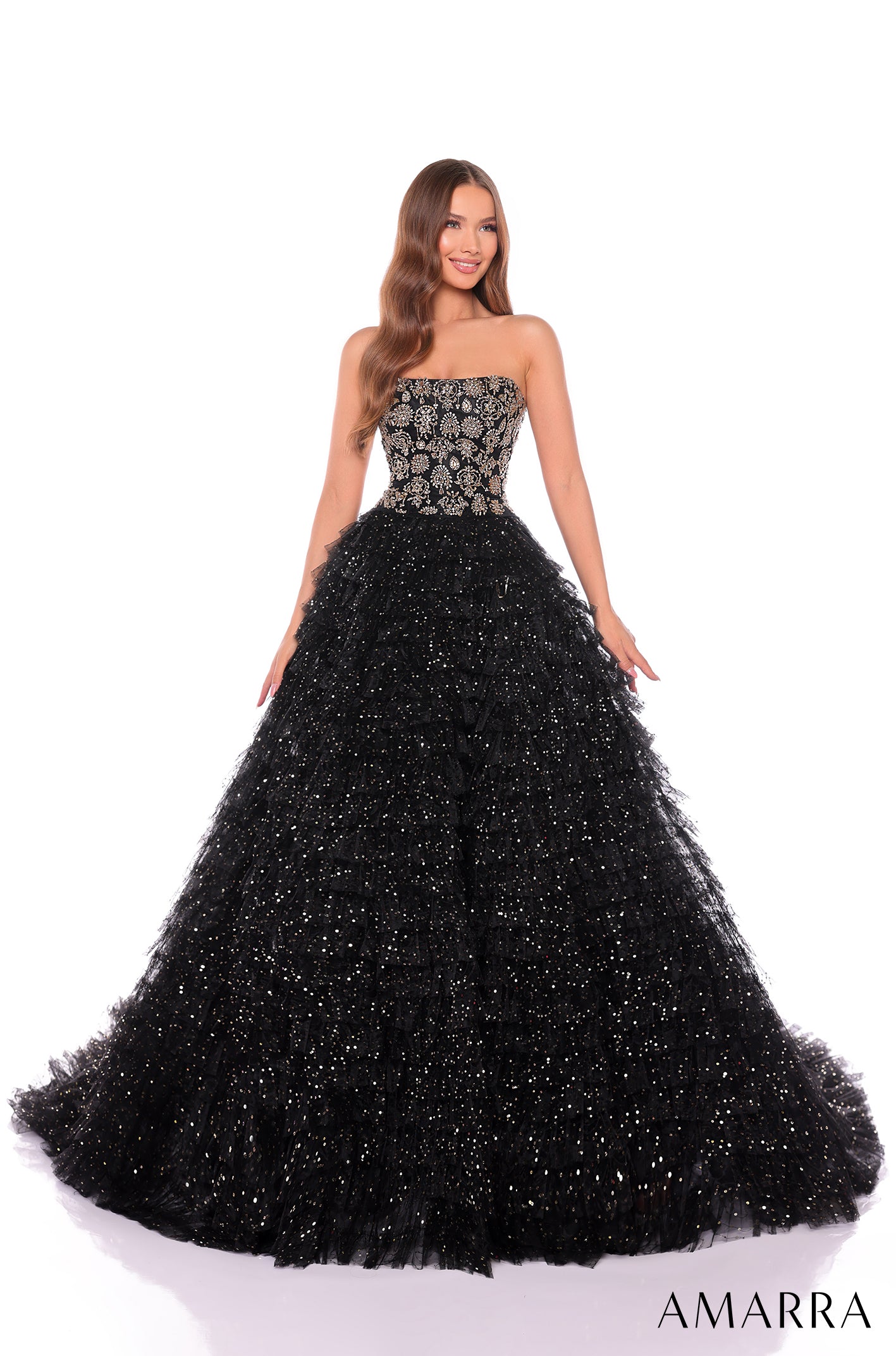 A model wears a strapless Black/Gold ballgown with sparkling tulle skirt and embellished bodice.