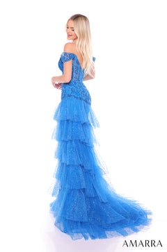 A blonde woman wears a blue off-shoulder tiered gown with sparkling tulle and a long train.