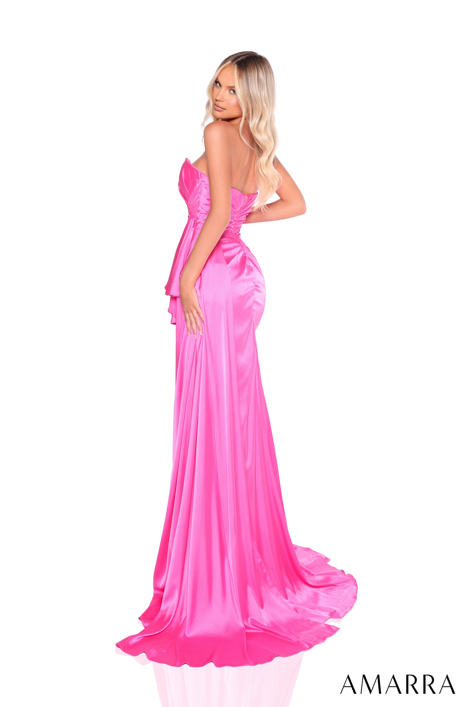 A blonde woman wears a vibrant pink strapless satin gown with a dramatic train and fitted silhouette.