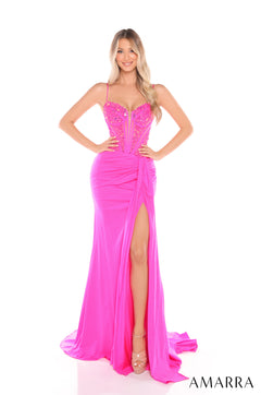 A woman wears a long fuchsia corset gown with a high slit and beaded bodice, posing against a white background.