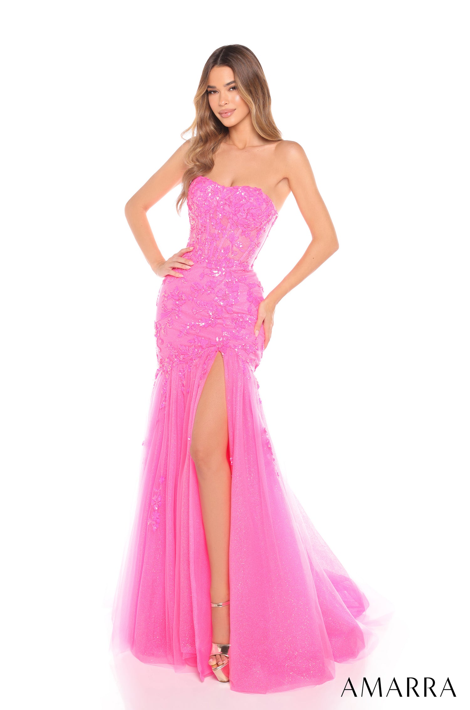A model wears a strapless, sequined fuchsia mermaid gown with a high slit and flowing tulle skirt.