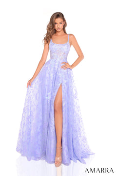 A model wears a flowing periwinkle lace gown with a high slit and fitted bodice by Amarra.