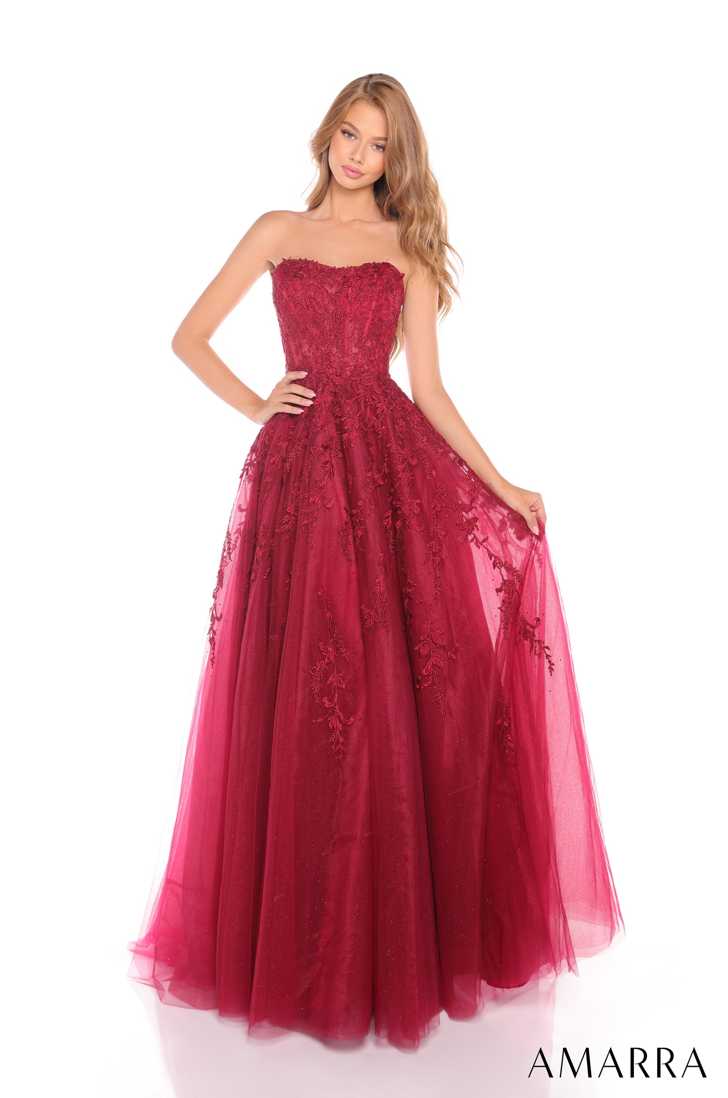 A model wears a strapless, floor-length ball gown in wine-colored lace and tulle with an embroidered bodice.