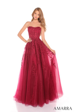 A model wears a strapless, floor-length ball gown in wine-colored lace and tulle with an embroidered bodice.