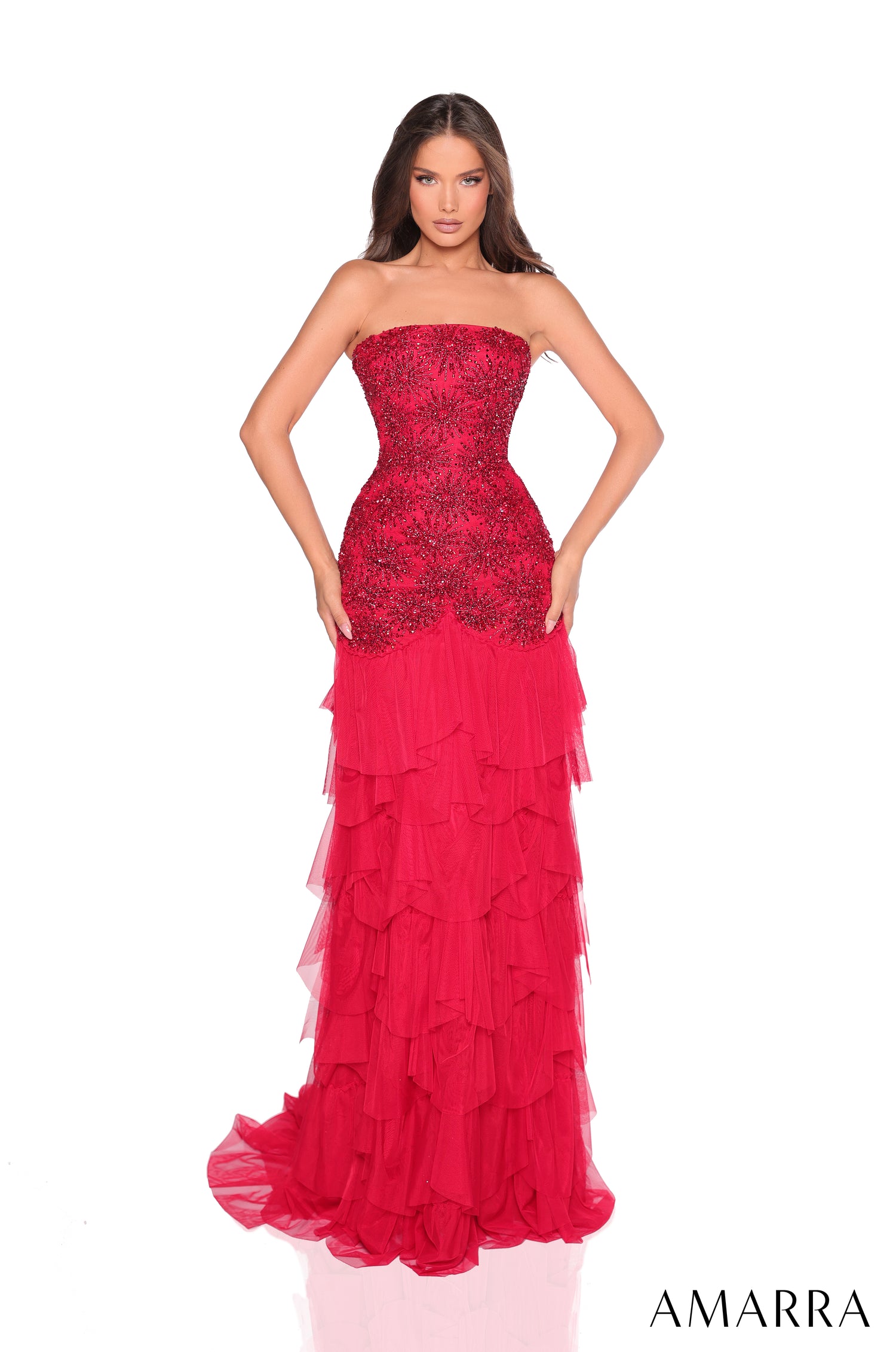 A strapless Red gown with sparkling bodice and tiered ruffled skirt, modeled by a woman against a white background.