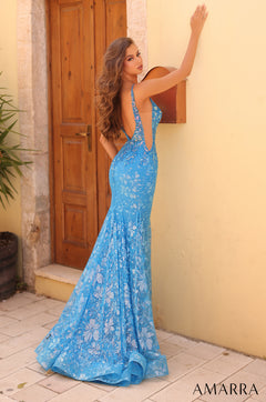 A long blue floral lace mermaid gown with an open back, posed against a wooden door and stone wall.