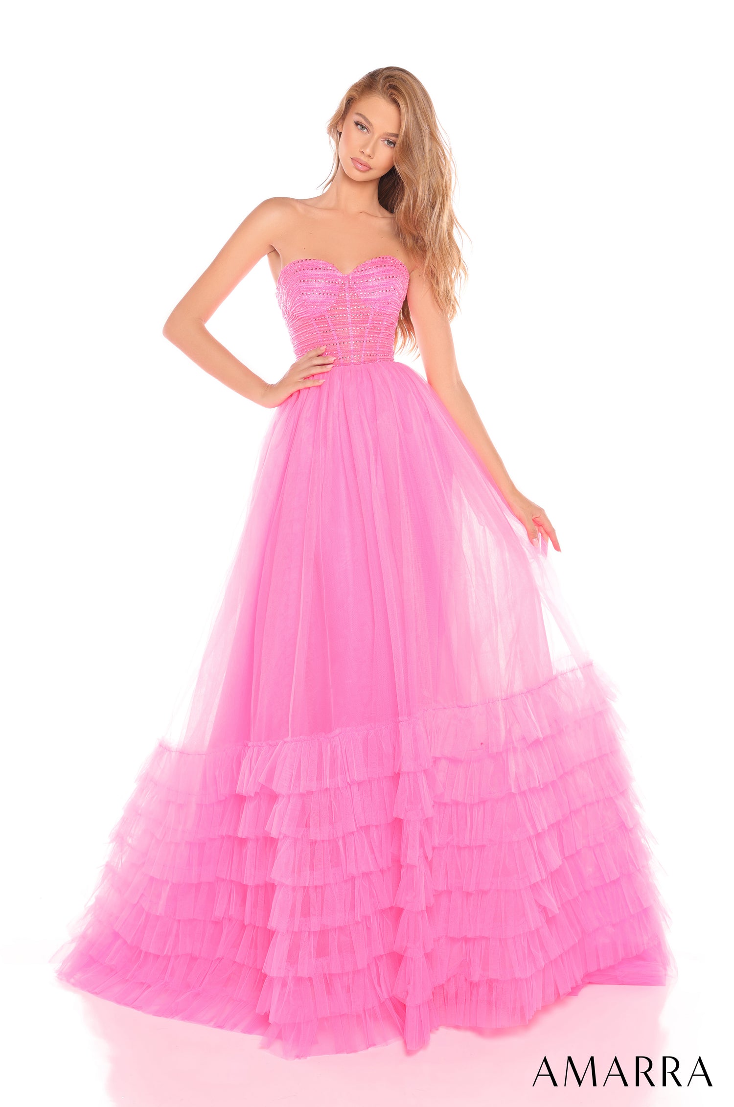 A model wears a sweetheart strapless ball gown in Hot Pink with tiered tulle skirt and beaded bodice.