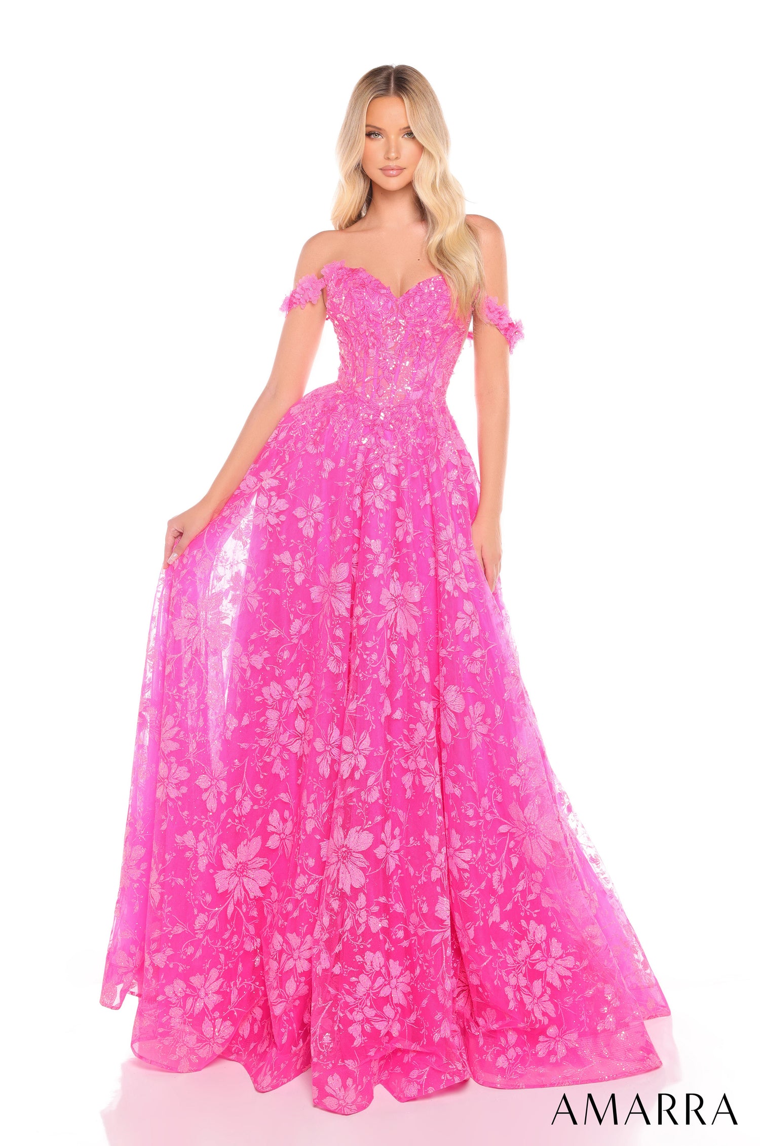 A woman wears a full-length fuchsia floral lace ballgown with off-shoulder design and sweetheart neckline.