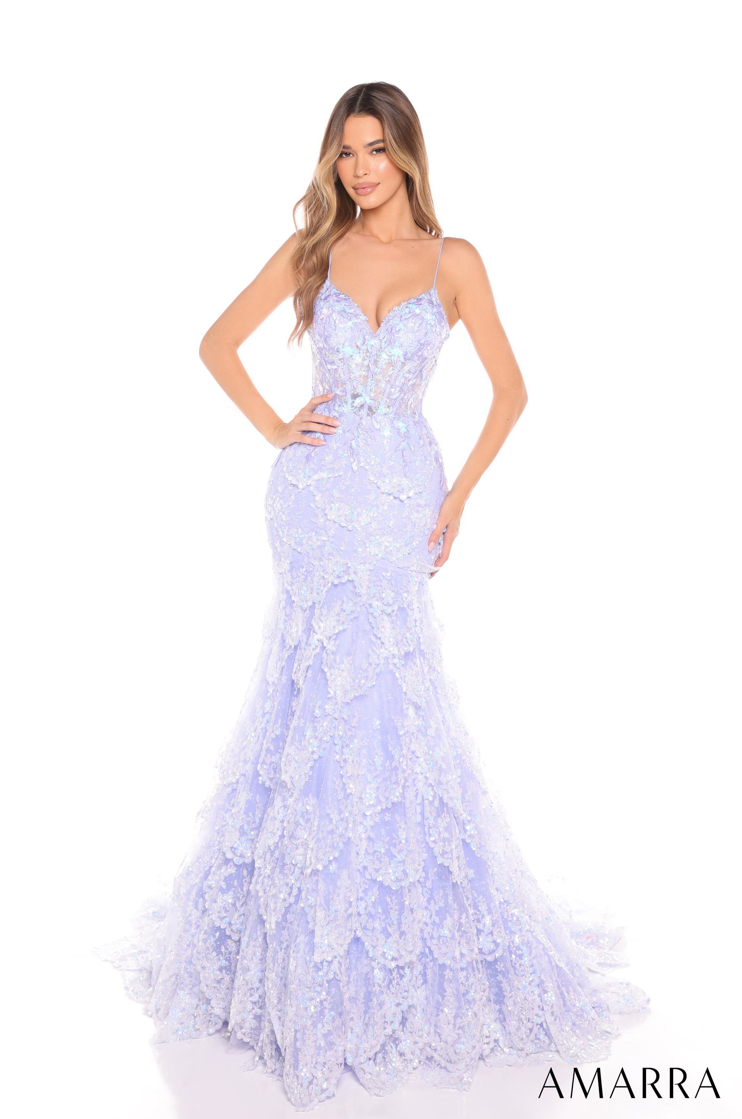 A woman wears a periwinkle lace mermaid gown with spaghetti straps and an elaborate, textured skirt.