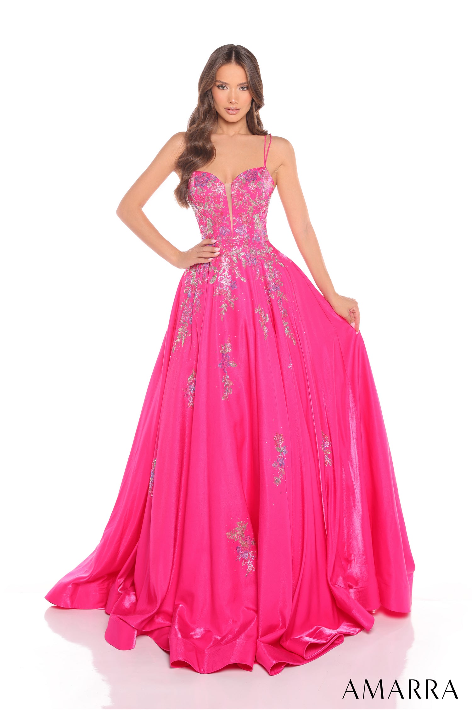 A model wears a fuchsia ball gown with intricate floral embellishments and a sweetheart neckline.