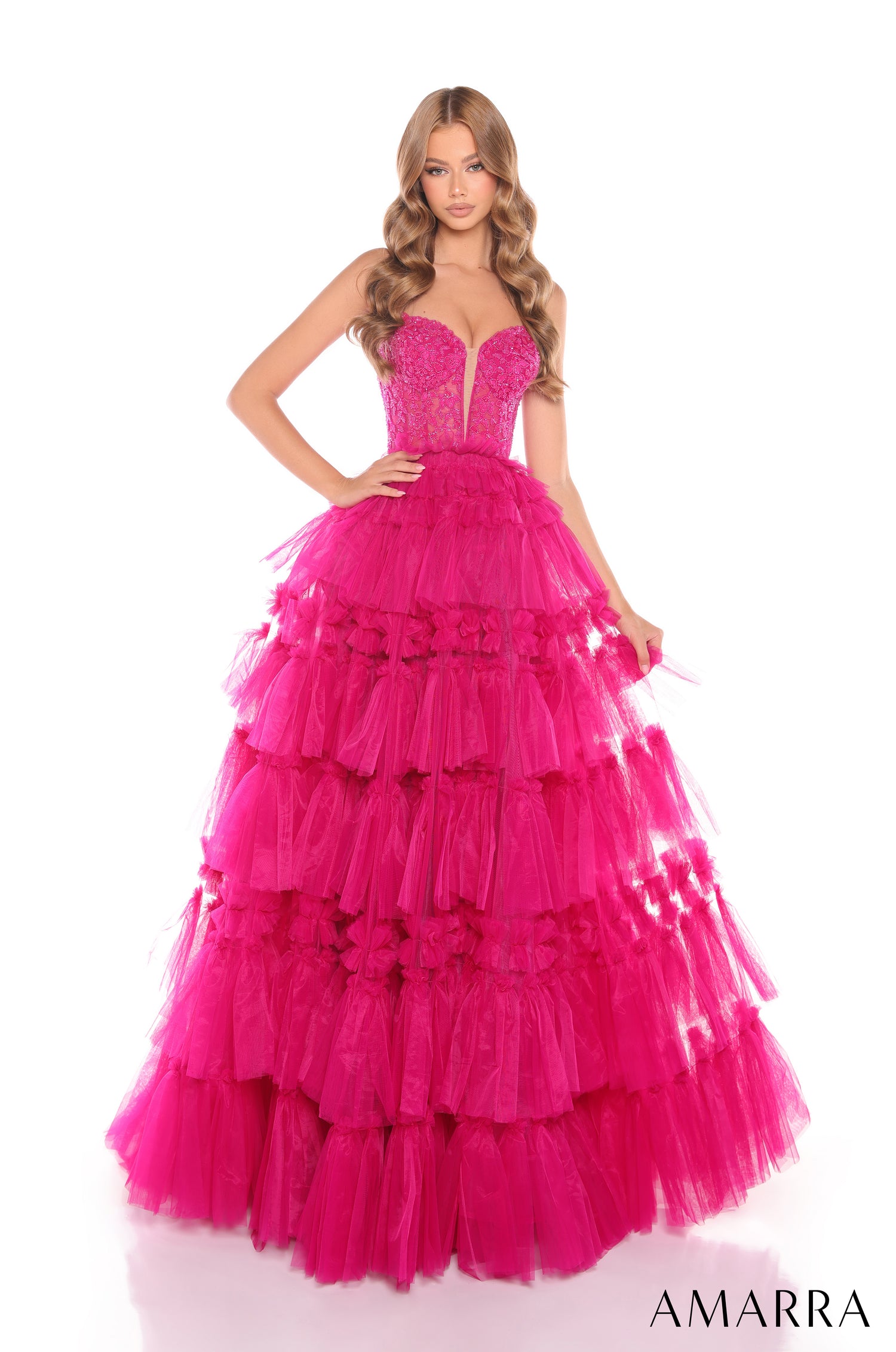 A woman wears a tiered, full-length ball gown in bright fuchsia tulle with a beaded sweetheart bodice.