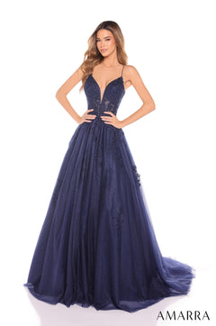 A woman wears a navy blue, floor-length ball gown with a plunging neckline and lace bodice.