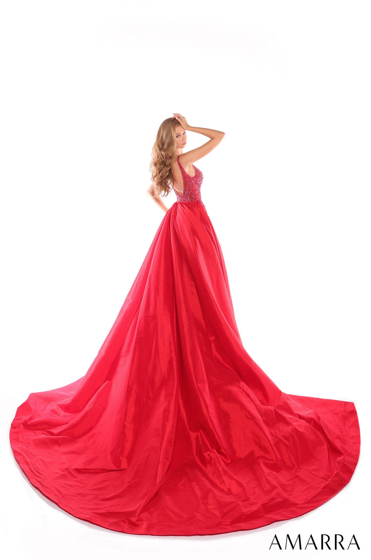 A woman wears a vibrant red ballgown with a beaded bodice and sweeping, voluminous skirt on a white background.