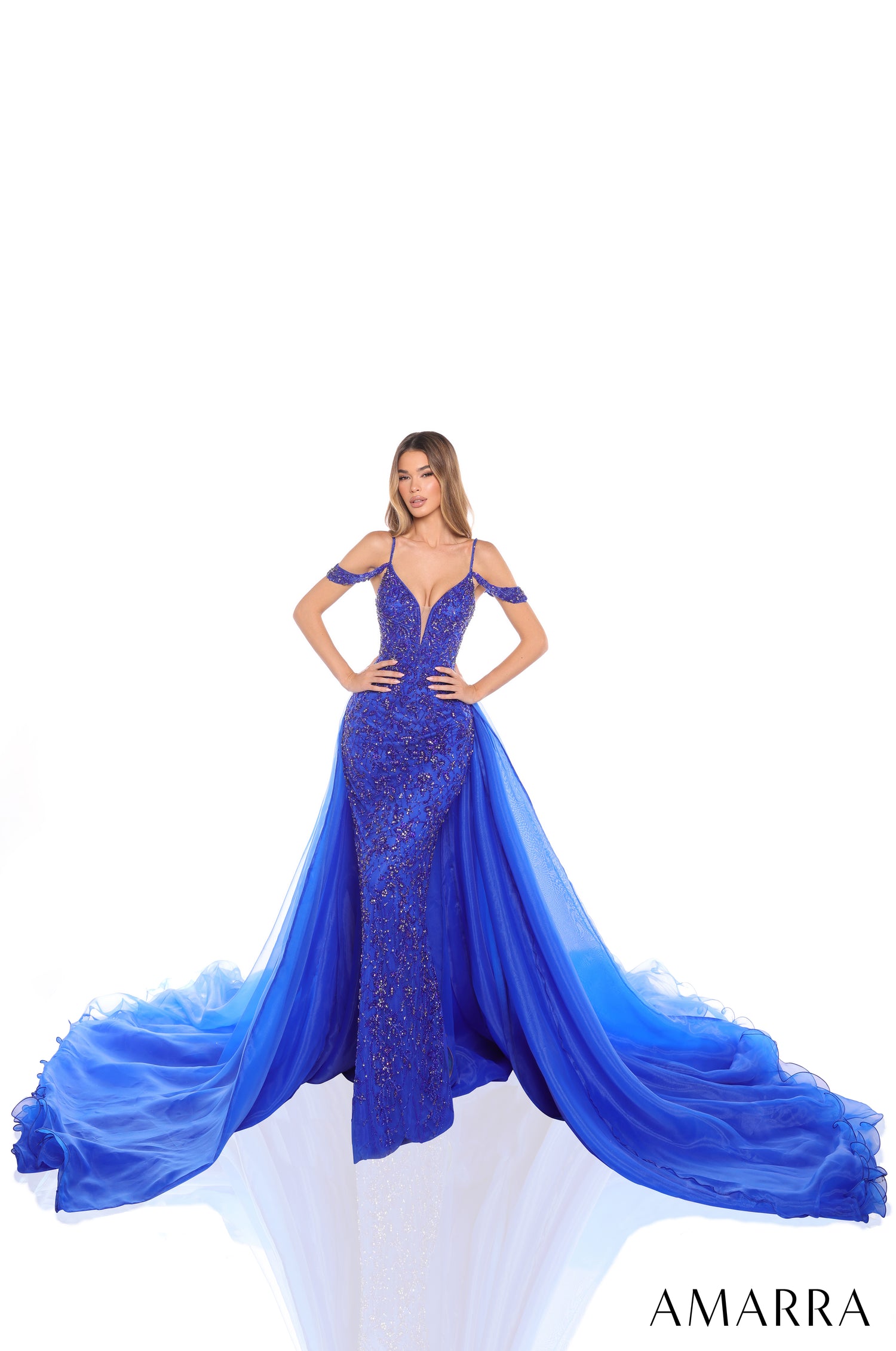 A fitted Royal Blue sequin gown with a dramatic tulle train, worn by a model against a white background.
