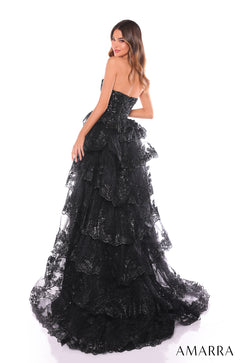 A strapless black sequined ball gown with tiered lace layers and a dramatic train, worn by a model.