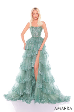 A model wears a sage green, multi-tiered ball gown with sparkling lace and a thigh-high slit.