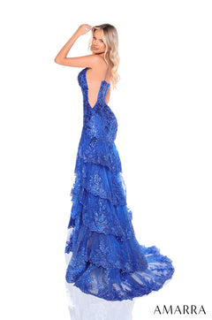 A model wears a royal blue, tiered, shimmering evening gown with a low back and long train.