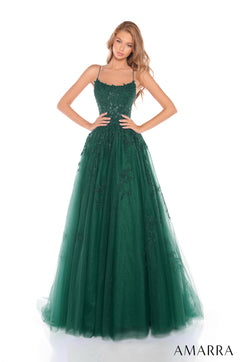 A floor-length emerald green tulle gown with lace bodice and spaghetti straps, worn by a model posing elegantly.