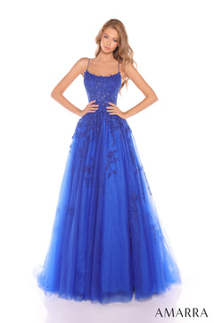 A woman wears a royal blue lace and tulle ball gown with spaghetti straps and an embellished bodice.