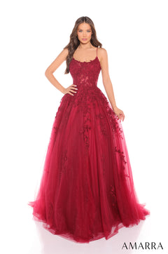 A woman wears a wine-colored ball gown with lace appliqués and a full tulle skirt.