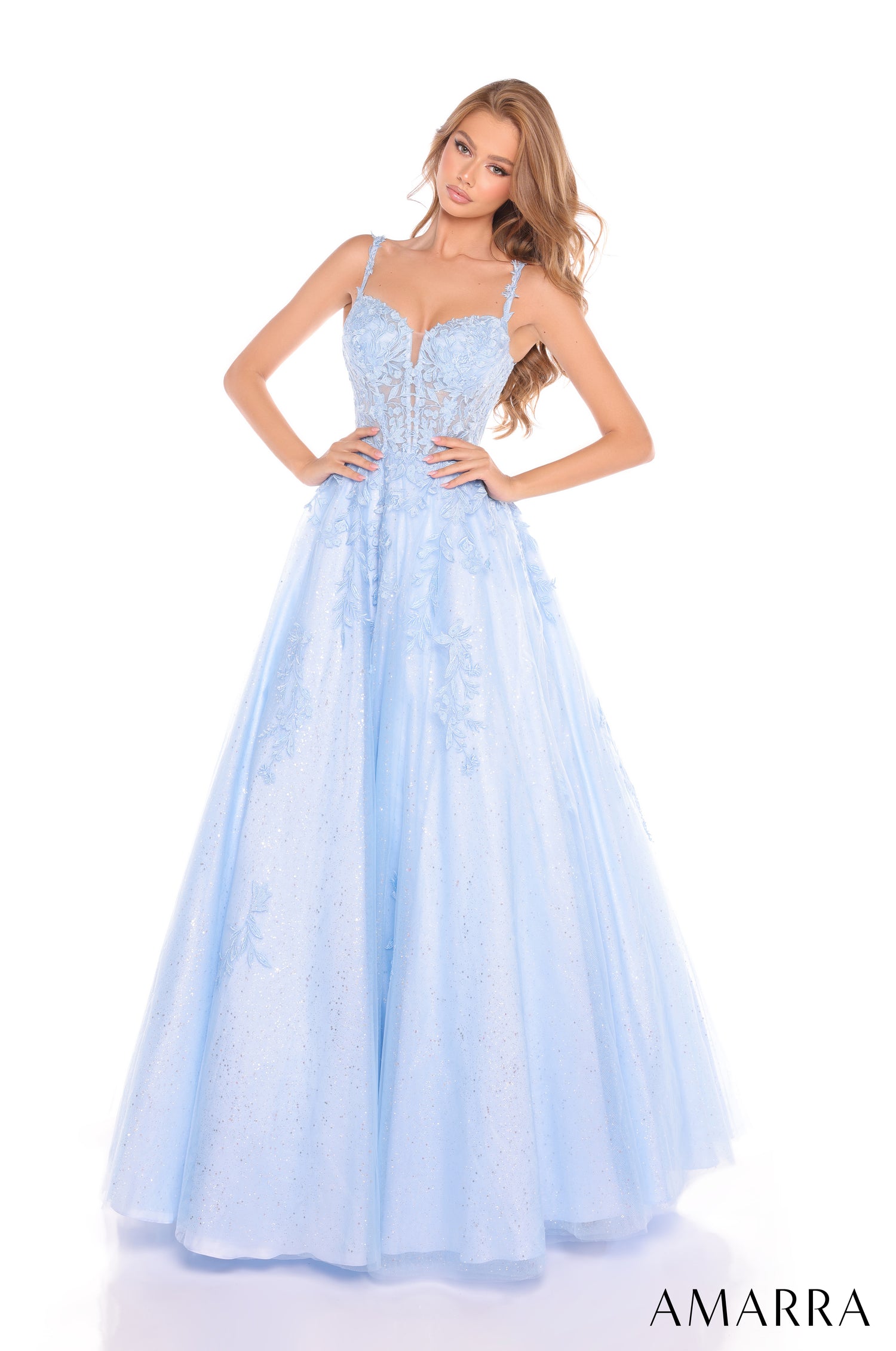 A model wears a light blue corseted ball gown with delicate floral embellishments and a full, flowing skirt.