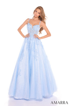 A model wears a light blue corseted ball gown with delicate floral embellishments and a full, flowing skirt.