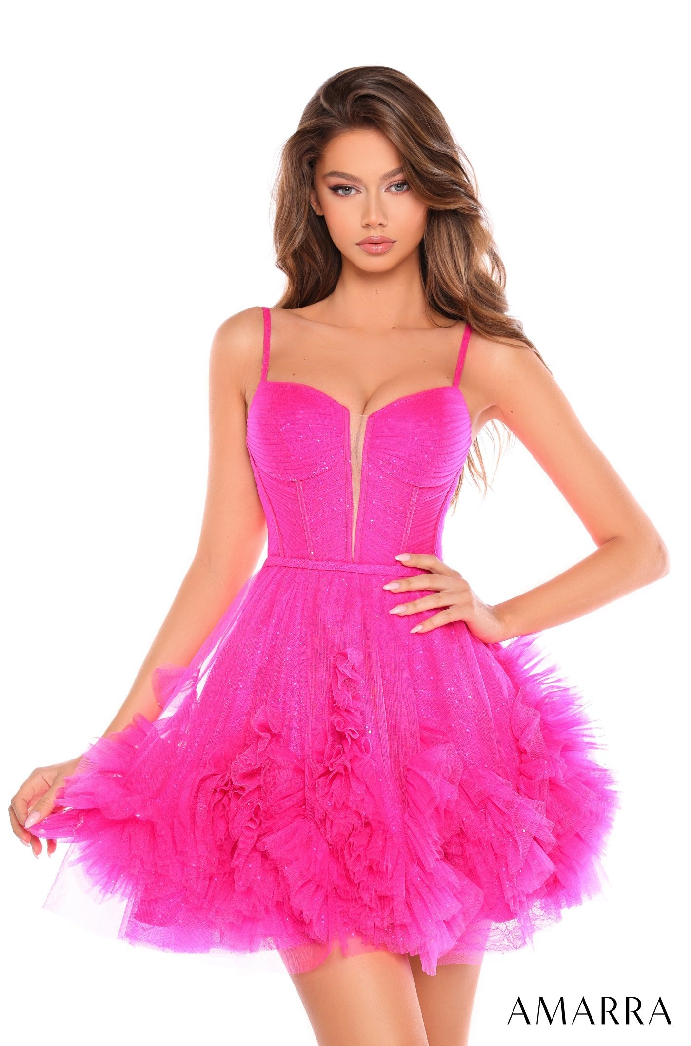 A model wears a neon pink ruffled tulle corset dress with sparkly details and a voluminous skirt.