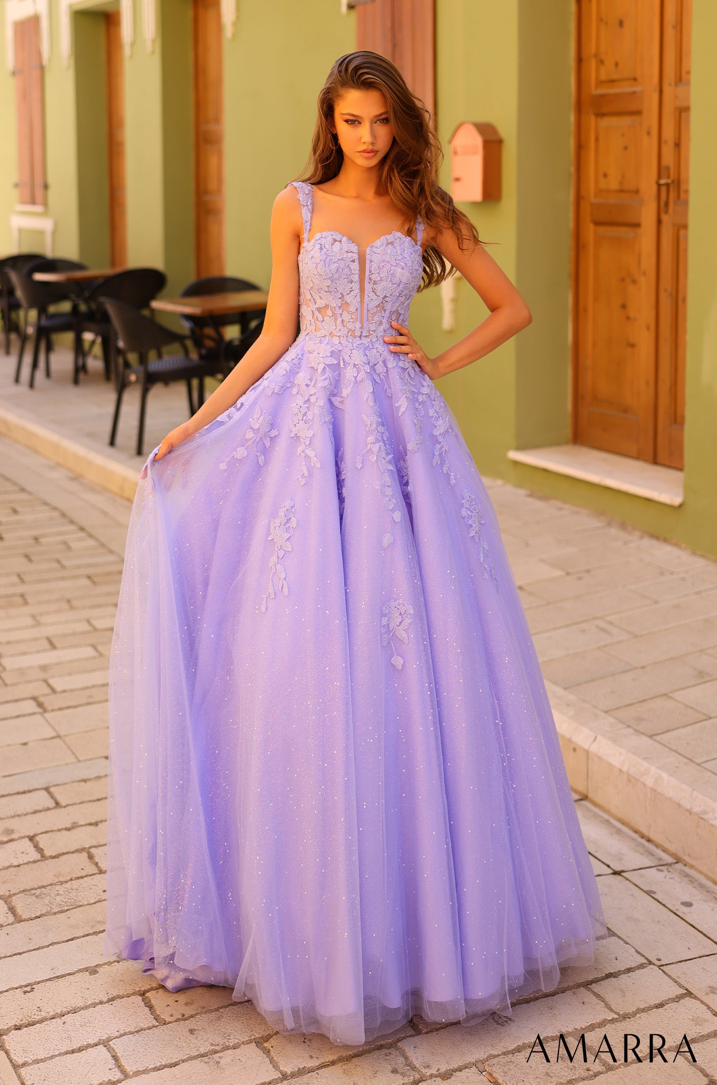 A lavender ball gown with floral appliqués and a sparkling tulle skirt, styled on a model in an outdoor setting.