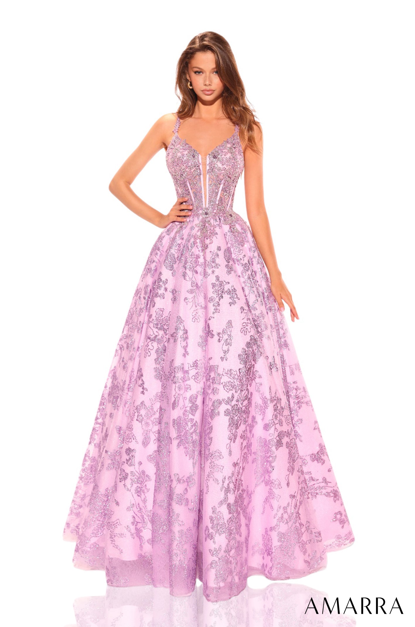 A model wears a lilac ball gown with floral lace detailing and a corseted bodice.