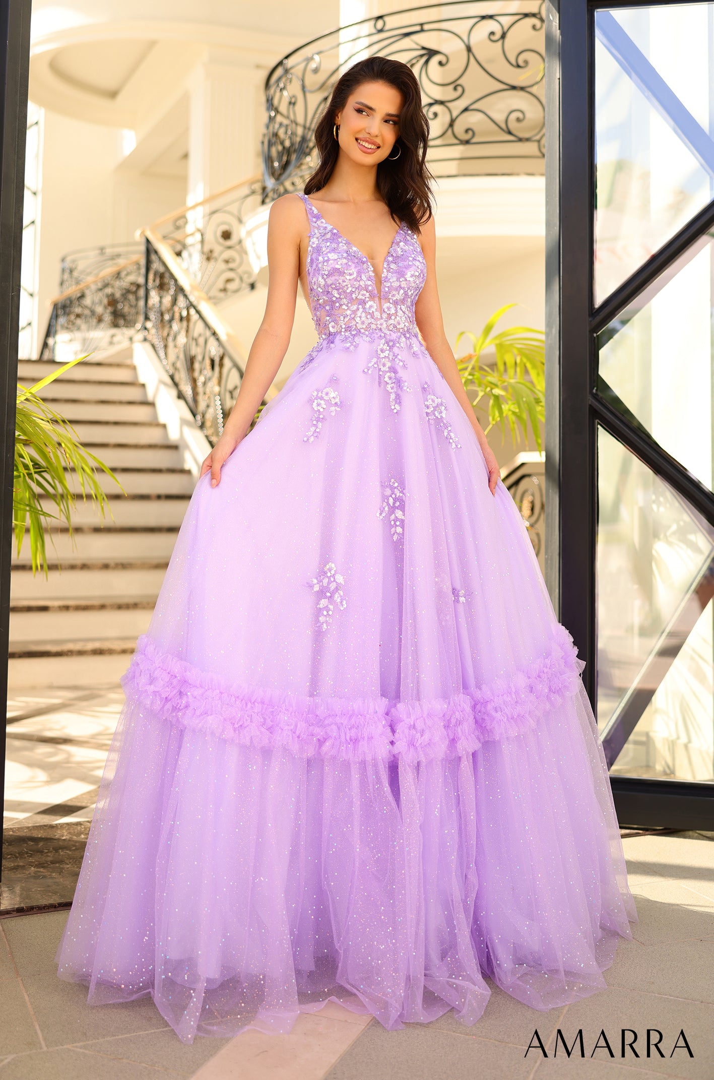 A lavender ball gown with floral embellishments and a voluminous tulle skirt, posed on an elegant staircase.