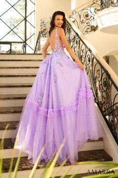A woman wears a lavender tulle ball gown with floral appliqués, posing on an ornate staircase.