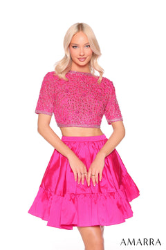 A woman wears a fuchsia two-piece dress with a beaded crop top and tiered skirt by Amarra.