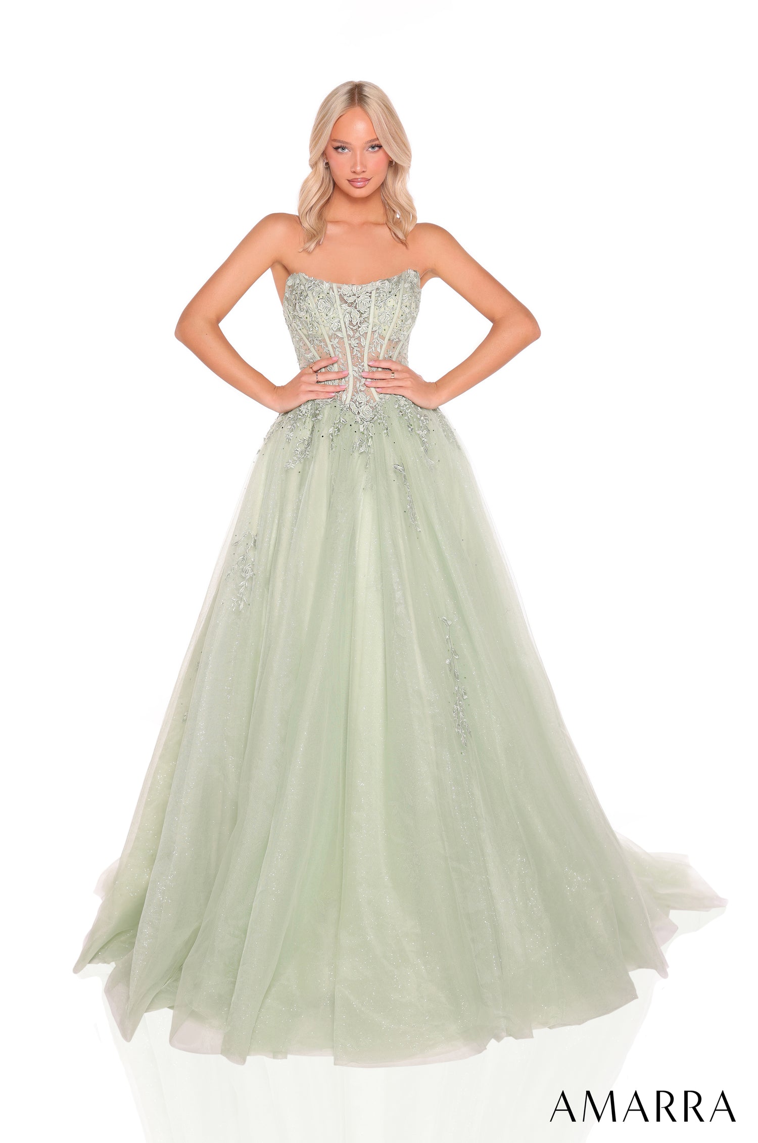 A model wears a strapless sage green ball gown with an embellished corset bodice and flowing tulle skirt.