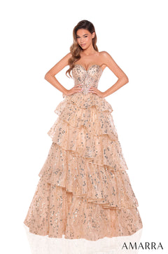 A strapless Gold ballgown with tiered ruffles and sparkling sequin embellishments, modeled by a woman posing elegantly.