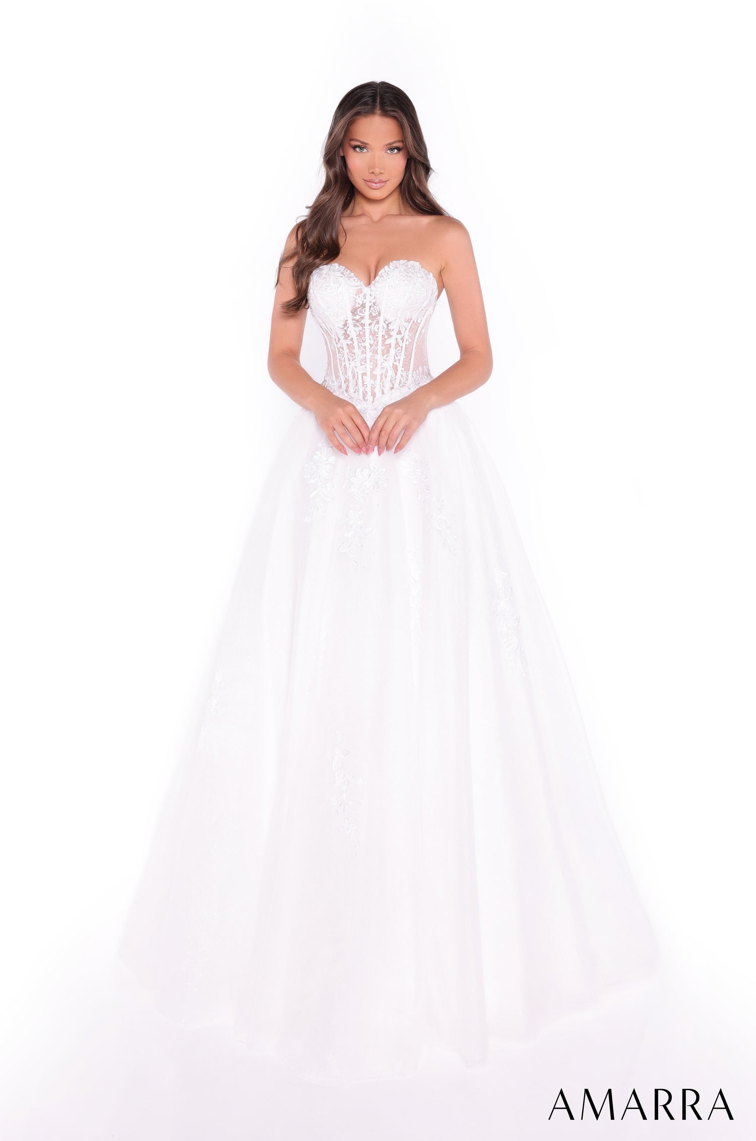 A model wears an ivory strapless wedding gown with a corset bodice and full tulle skirt from Amarra.