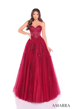 A strapless red ball gown with floral lace detail and a fitted bodice, worn by a model against a white background.
