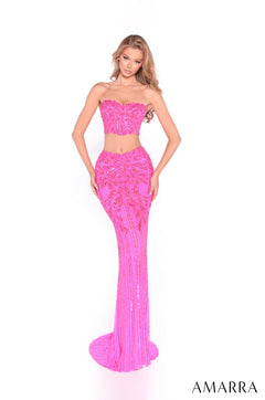 A model wears a strapless two-piece neon pink sequin gown with a fitted mermaid skirt.