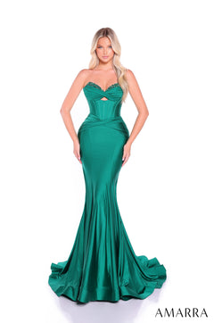 A woman wears a fitted emerald green satin mermaid gown with a corset-style bodice and dramatic train.