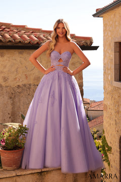 A woman wears a stunning lilac strapless ball gown with lace details, posing on a stone terrace with a coastal view.