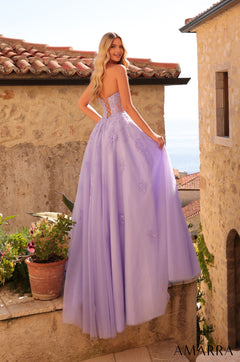 A lavender ballgown with floral details stands on a stone terrace with terracotta rooftops in the background.