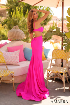 A slender model wears a vibrant pink cut-out gown with a long train on a pink outdoor patio.